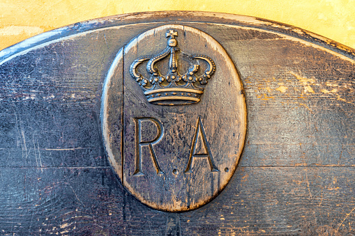 Seville, Spain - December 22, 2023: Royal coat of arms on a wooden bench in the Alcazar of Seville, Spain. The Alcazar, which dates back to the 12th century, forms part of a UNESCO World Heritage site.