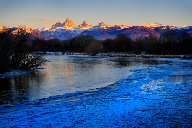 Grand Tetons Mountain Range or Teton Mountains with snow and sunset light with river and ice