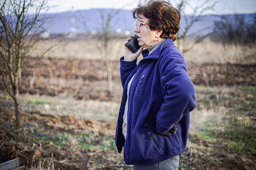 Mature woman using smart phone on agricultural field