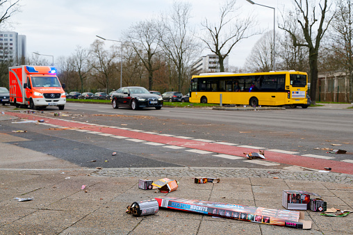 Berlin, Germany - January 1, 2024: Street scene with fireworks debris in the foreground and a fire department ambulance in the background.