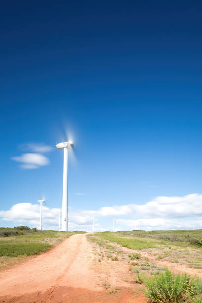 Wind turbines with spinning blades captured with motion blur under a blue sky with clouds