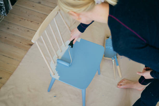 istock Crafting at home: Woman using a paint roller to renovate chair 1900179437