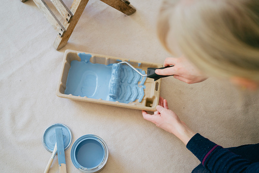 Hands-on artistry: Woman preparing to use blue paint from a tray.
