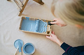 DIY enthusiast rolling a paint roller in a paint tray