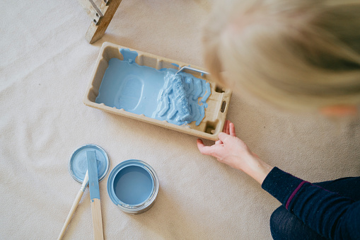 Crafting with color: Woman stirring blue paint in a tray for her project.