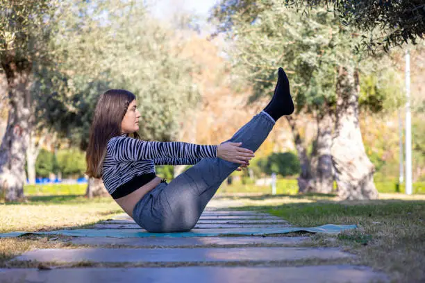 Photo of young woman performing yoga in the green garden