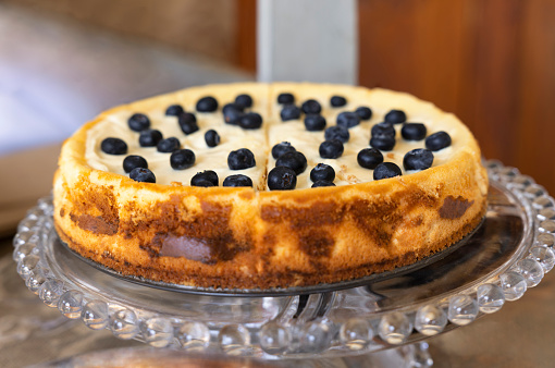 flea market shop, blueberry milk tart with cinnamon on a glass display tray, cut in slices ready for serving.