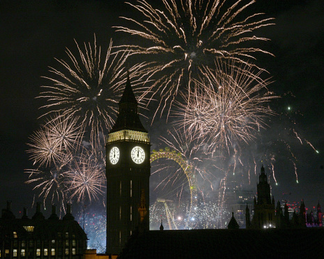 Iconic Big Ben surrounded by midnight fireworks at New Year, London UK