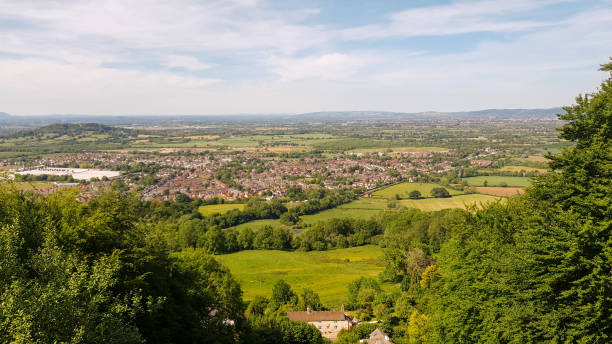 istock Panoramic view of a lush valley with residential areas, green fields, and trees under a clear blue sky. 1900283066