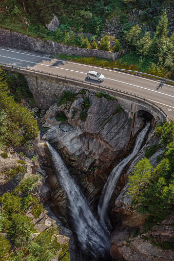 An idyllic scene of two waterfalls merging under the road leading to the Furkapass