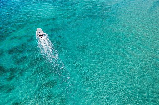Aerial photo of the boat taking tourists to the reef in crystal-clear lagoon waters