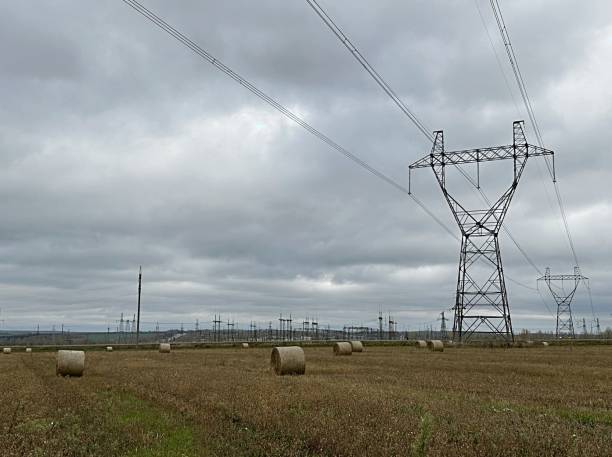istock high voltage power lines, high power overhead power lines, high voltage pylons, also known as power pylons, in fields with haystacks. autumn 1900372387