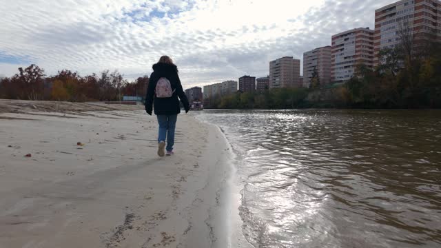 Tourist woman strolling quietly along the bank of the Pisuerga River in Valladolid, Spain.