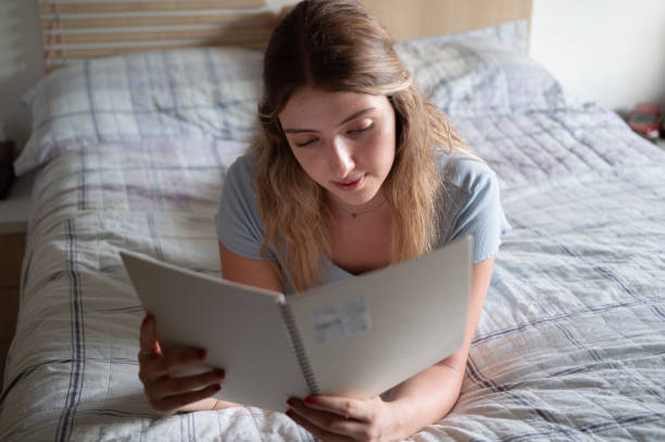 istock Beautiful young woman studying lying down for exams during the day 1900388329