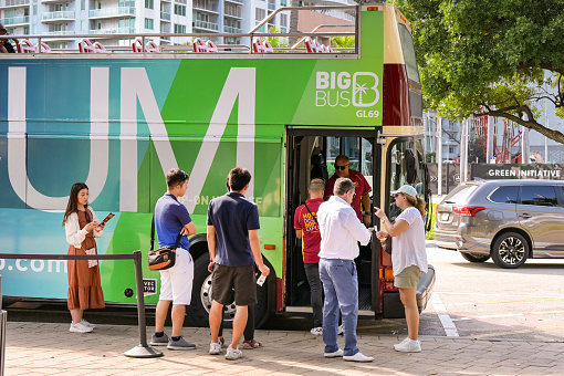 Miami, Florida, USA - 3 December 2023: Tourists catching a hop on hop off sightseeing bus in downtown Miami