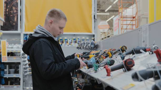 istock Cordless power tools. Counter with power tools. A man in a hardware store chooses electrical goods. A buyer in a store chooses a screwdriver. I buy a screwdriver at a hardware store. 1900445457