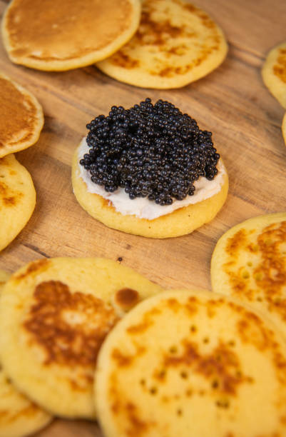 istock Blinis with black caviar and cream cheese, on a festive dish, mini pancakes, an elegant appetizer 1900454174