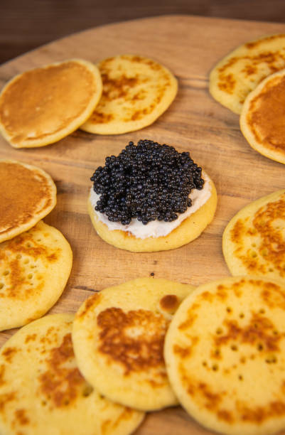 istock Blinis with black caviar and cream cheese, on a festive dish, mini pancakes, an elegant appetizer 1900454176