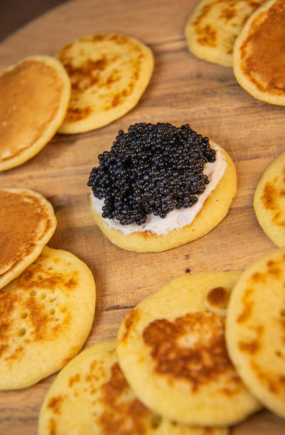 istock Blinis with black caviar and cream cheese, on a festive dish, mini pancakes, an elegant appetizer 1900454177