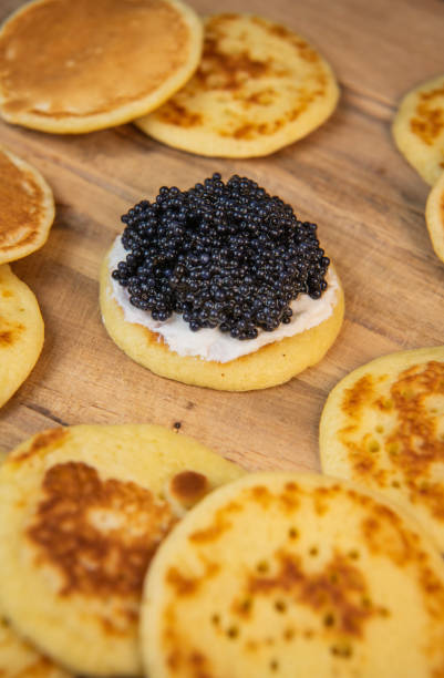 istock Blinis with black caviar and cream cheese, on a festive dish, mini pancakes, an elegant appetizer 1900454178
