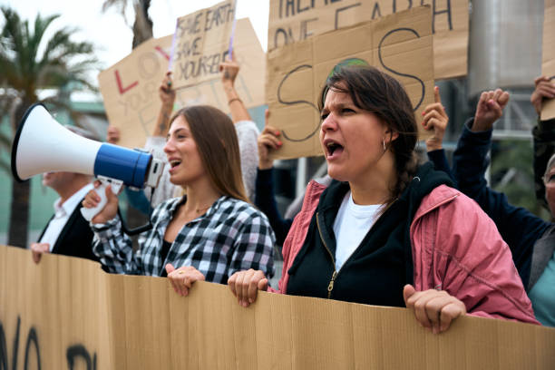 istock Angry and rebellious woman speaking and protesting with megaphone at demonstration at climate change 1900611671