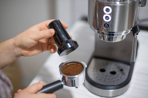 istock Happy young woman making morning coffee with coffee machine 1900613198
