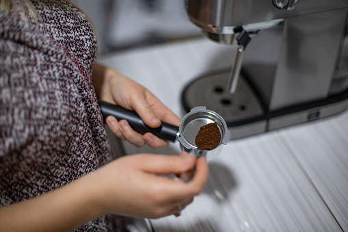 Happy young woman preparing morning coffee with coffee machine