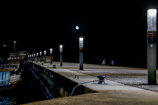 streetlights along a pier and a couple holding hands.