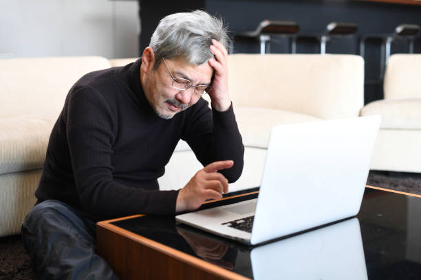 istock An older Asian man with gray hair is having trouble operating a laptop computer. 1900670718