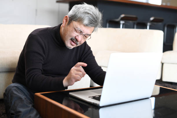 istock An older Asian man with gray hair is having trouble operating a laptop computer. 1900670720