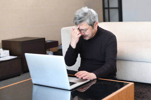istock An older Asian man with gray hair is having trouble operating a laptop computer. 1900670721