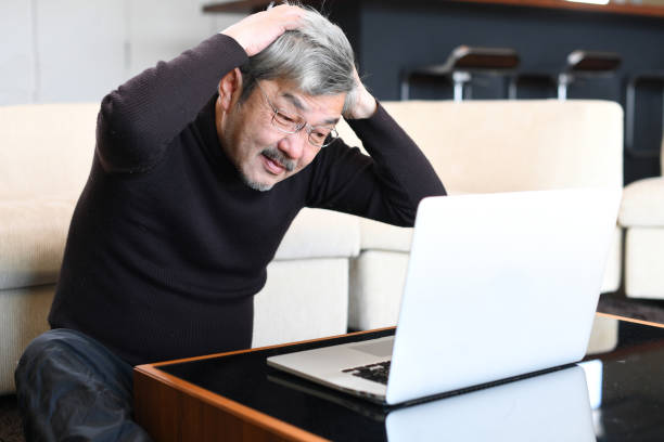 istock An older Asian man with gray hair is having trouble operating a laptop computer. 1900670956