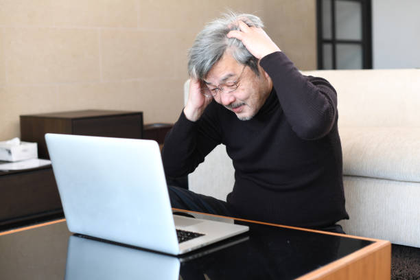 istock An older Asian man with gray hair is having trouble operating a laptop computer. 1900671228