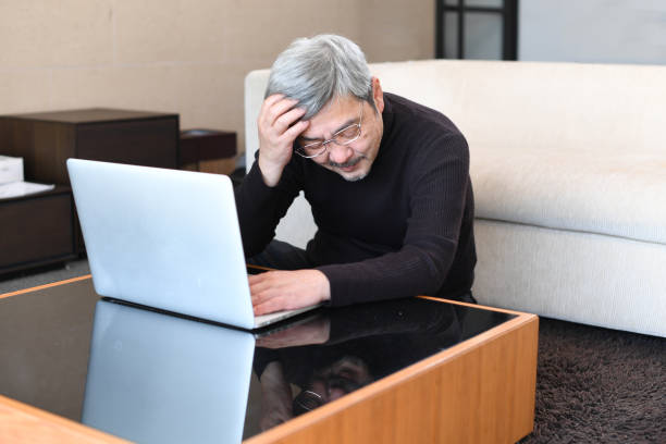 istock An older Asian man with gray hair is having trouble operating a laptop computer. 1900692035