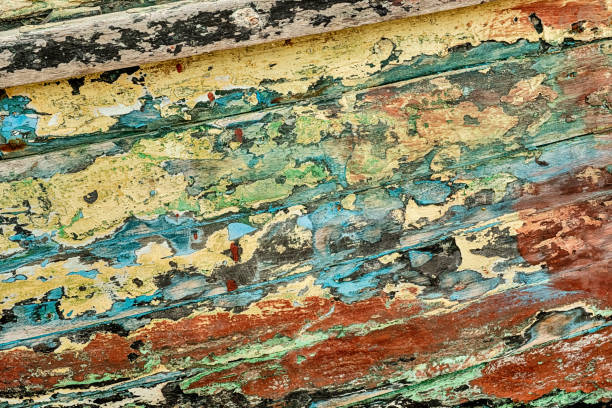 An abstract bacgkround is seen in the paint flakes peeling off the hull of a fishing boat painted with many different colors of paint.