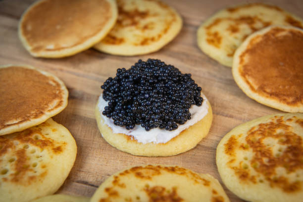 istock Blinis with black caviar and cream cheese, on a festive dish, mini pancakes, an elegant appetizer 1900757310