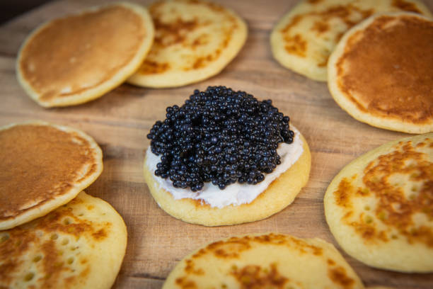 istock Blinis with black caviar and cream cheese, on a festive dish, mini pancakes, an elegant appetizer 1900757312