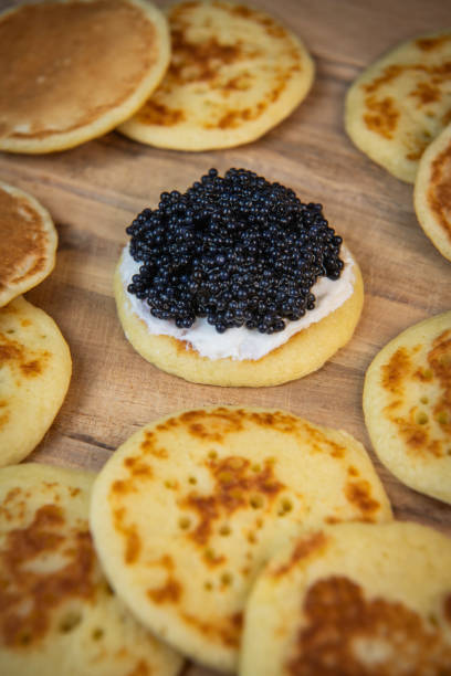 istock Blinis with black caviar and cream cheese, on a festive dish, mini pancakes, an elegant appetizer 1900757316