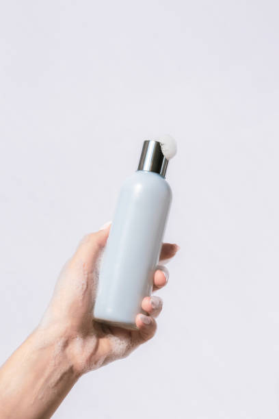istock Woman's soapy hand holding cosmetic blue bottle. Natural cosmetics concept. Mockup 1900845312