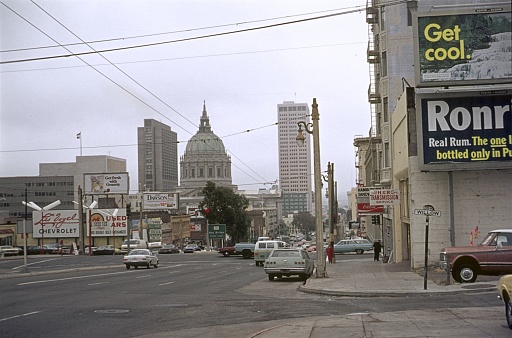 San Francisco, California, USA, 1975. Street scene on Van Ness Ave, with the dome of City Hall in the background. Also: buildings, cars and pedestrians.