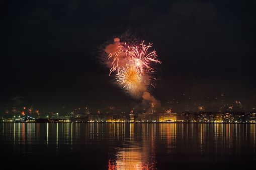 Series of fireworks above large residential area landscape at night. New Years Eve pyrotechnics at Thessaloniki, Greece seen from the city waterfront.