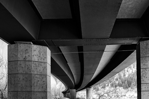 Recreation Path with Road Overpass Overhead - Black and white image of concrete curving road structures over recreation path. Graphic lines, shapes and textures with diminishing perspective.