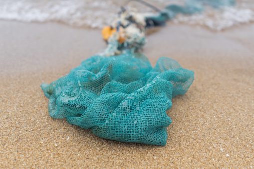 Blue tangled fishing nets washed up on the shore. An environmental issue as the nets are a dangerous form of plastic pollution providing a hazard to ocean wildlife.