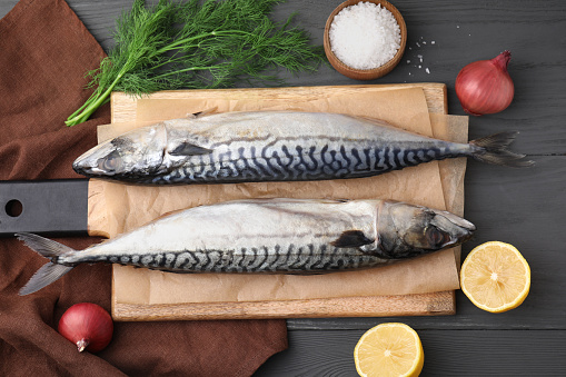 Tasty salted mackerels and products on gray wooden table, flat lay