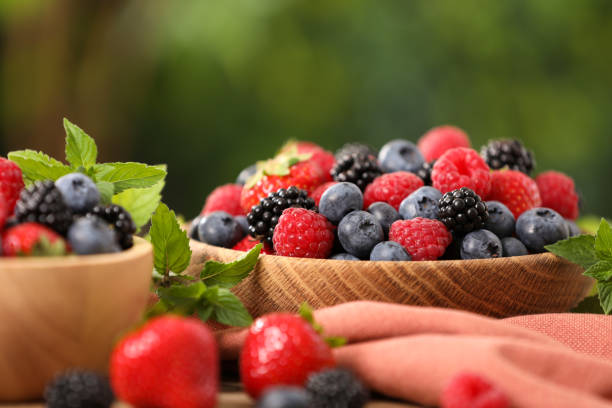 istock Bowls with different fresh ripe berries and mint on table outdoors, closeup 1900995749