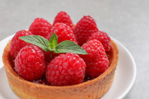 istock Tartlet with fresh raspberries and mint on light table, closeup. Delicious dessert 1900996590