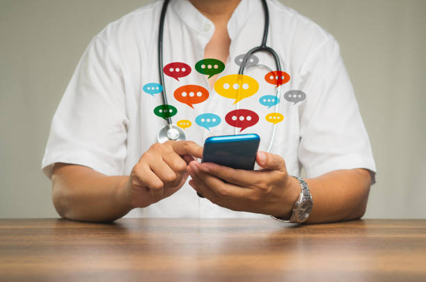 istock Physician using a smartphone with colorful chat icons on application digital web and social media while sitting at the table 1901076302