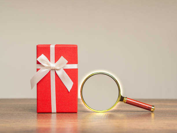 istock Red gift box and a magnifying glass on a wooden table. 1901083536