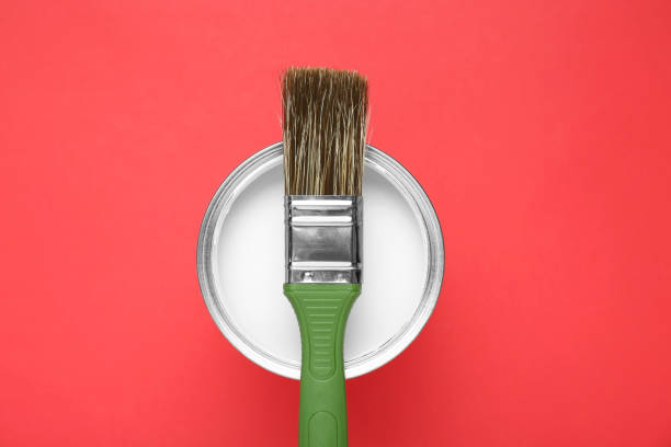 istock Can of white paint with brush on red background, top view 1901091707
