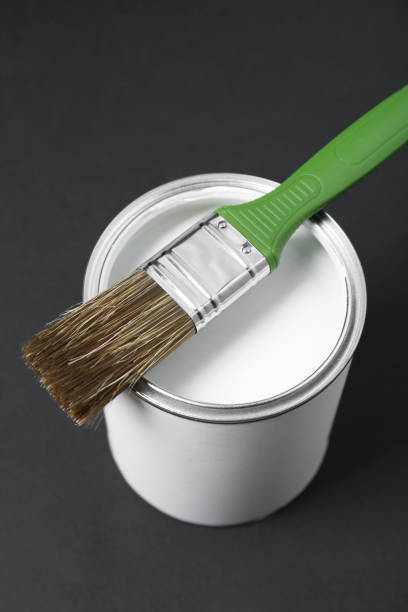 istock Can of white paint with brush on black background 1901094280